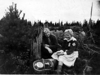Marjassa  Vuokko Salminen (o.s. Suominen, nojaa kantoon) ja Raili Dickman (marjakuppi kädessä) marjassa, edessä ämpäri ja kori, vasemmalla mänty, takana sammaleinen kivi.