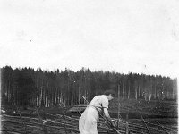 Kaivolla  Haikkalan pihassa emäntä Ida Ilmonen (o.s. Saaniemi) kaataa kaivosta nostamaansa vettä ämpäriin.