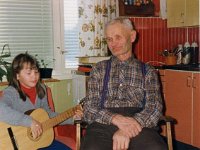Pitk(76)  Armi Lehtinen soittaa Pitkälän keittiössä kitaraa, Hänen isänisänsä Paavo Lehtinen (27.6.1904 - 26.7.1986) eli Pitkälän Paavo kuuntelee vieressä.