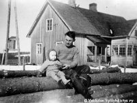 suljula(29)  Veli Häyrynen (4.10.1911 - 14.11.1986) istuu lapsensa (joko Teuvo s. -37, Raimo s. -39, Ari s. -41 tai Ritva s. -49) kanssa pöllipinon päällä. Takana talo