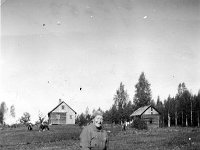 suljula(8)  Edla Valden (20.7.1893 - 12.4.1979) istuu kivellä Syrjälän talon takana. Taustalla kahden rakennuksen lisäksi lehmiä laiduntamassa ja pyykkiä narulla.