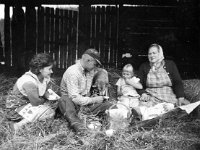 Vuorenpaa(17)  Hilja, Jaakko (s. 1939), Tuija ja Ida Vuorinen  (o.s. Lamminmäki, s. 1899) istuvat heinissä kahvitauolla heinän "talliamisesta". Jaakko tarjoaa lautaselta koirallekin.